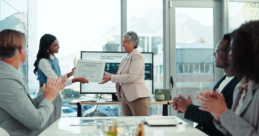 Black woman and White woman smiling at each other in a work meeting.