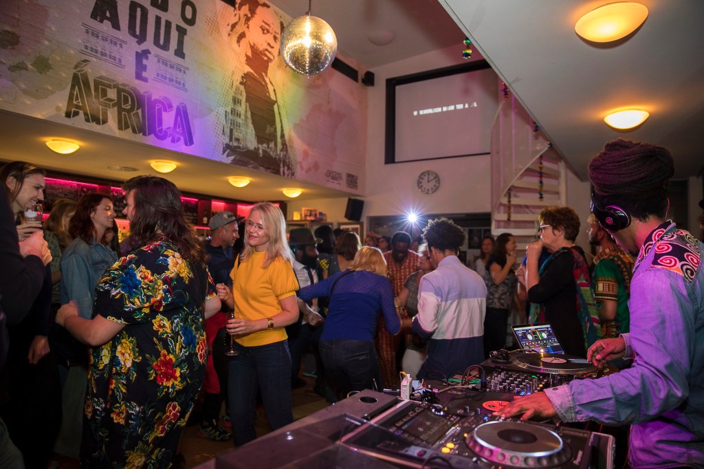 Group of people at a lounge listening to a disc jockey.