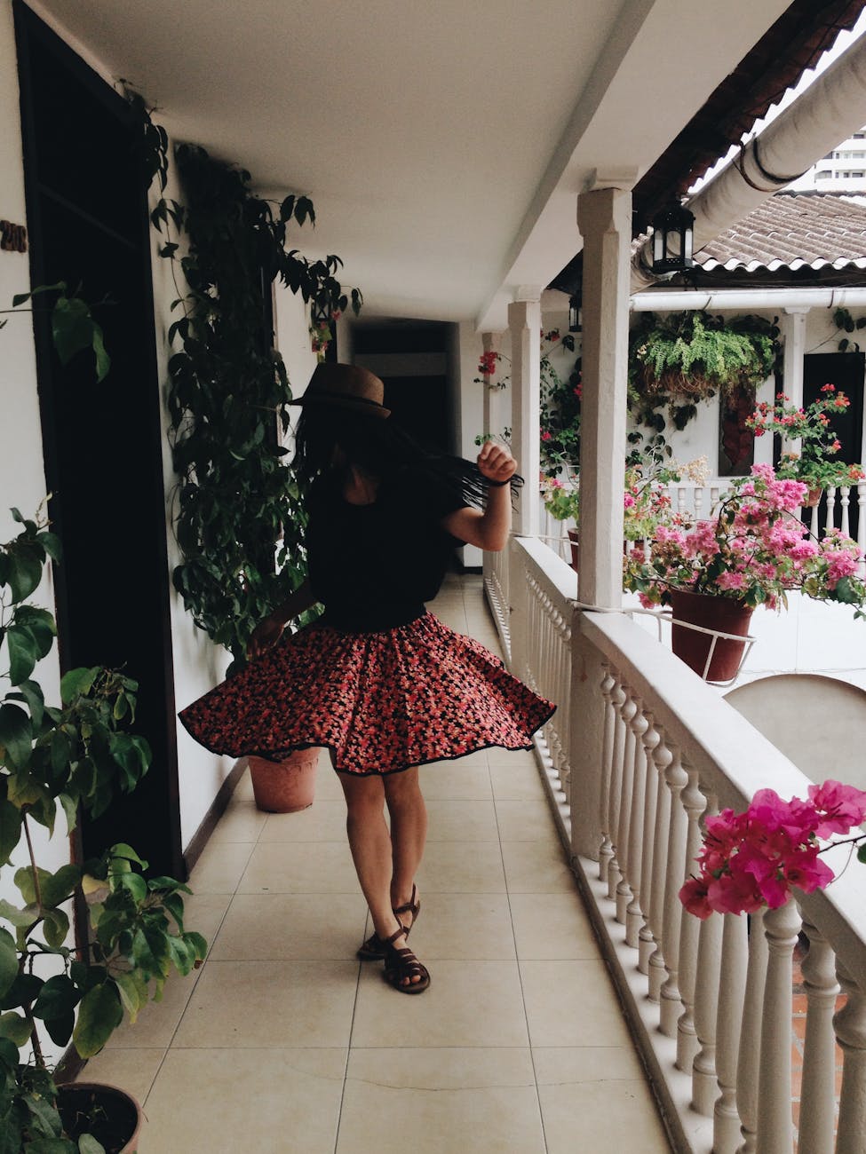 Woman walking with a colorful skirt on, sandals and a hat.