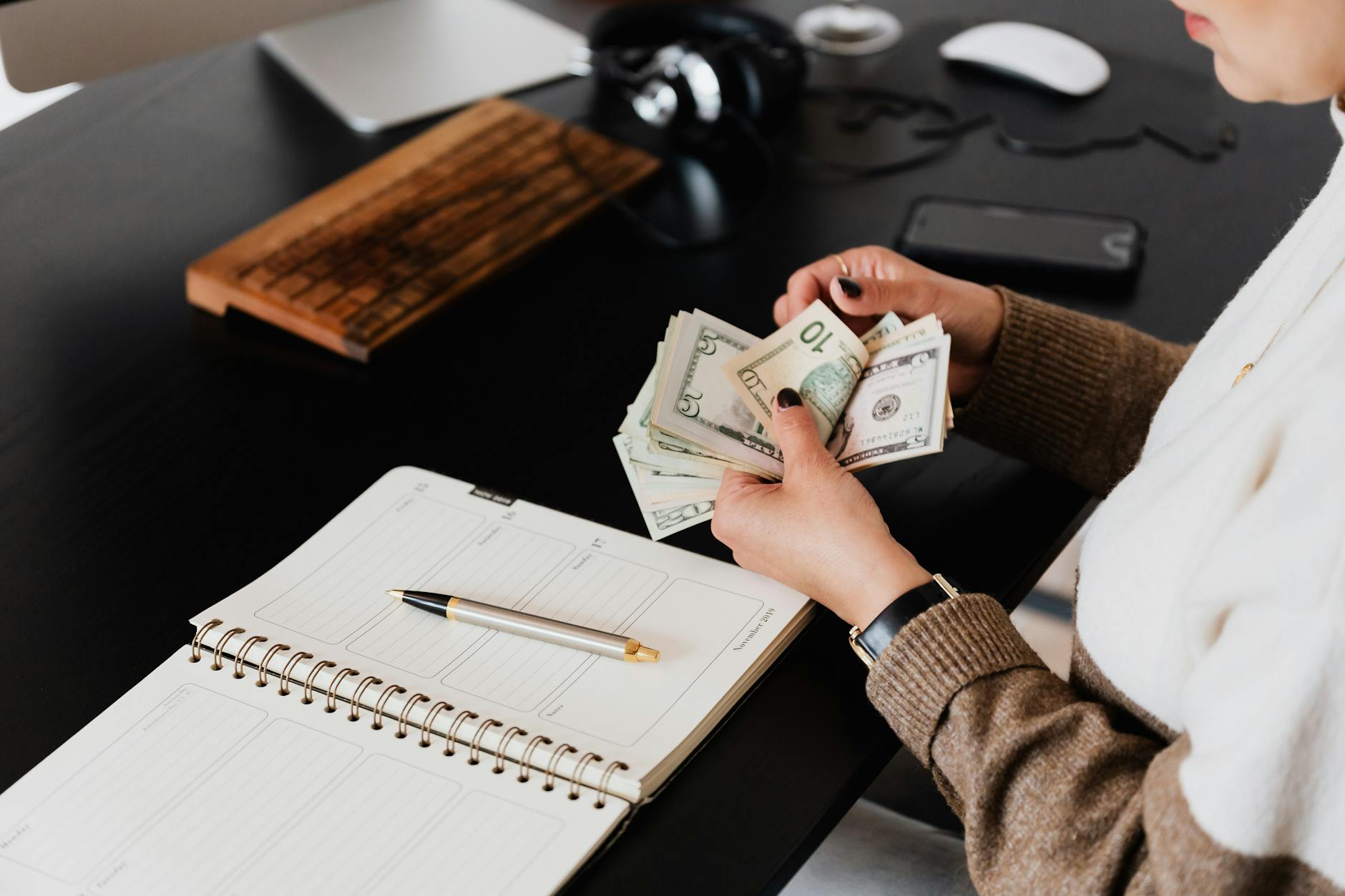 Pic of woman at desk counting money and budgeting.