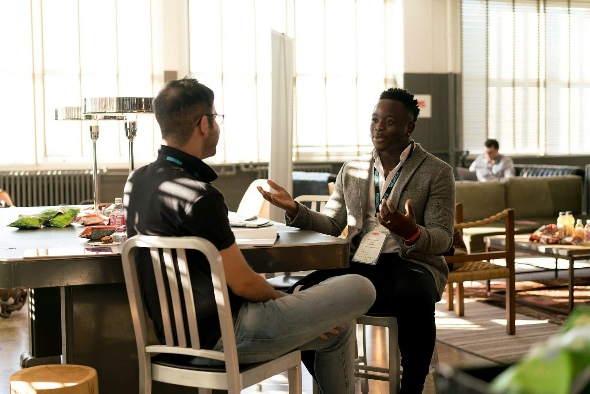 Black man and White man sitting at a table talking and smiling.
