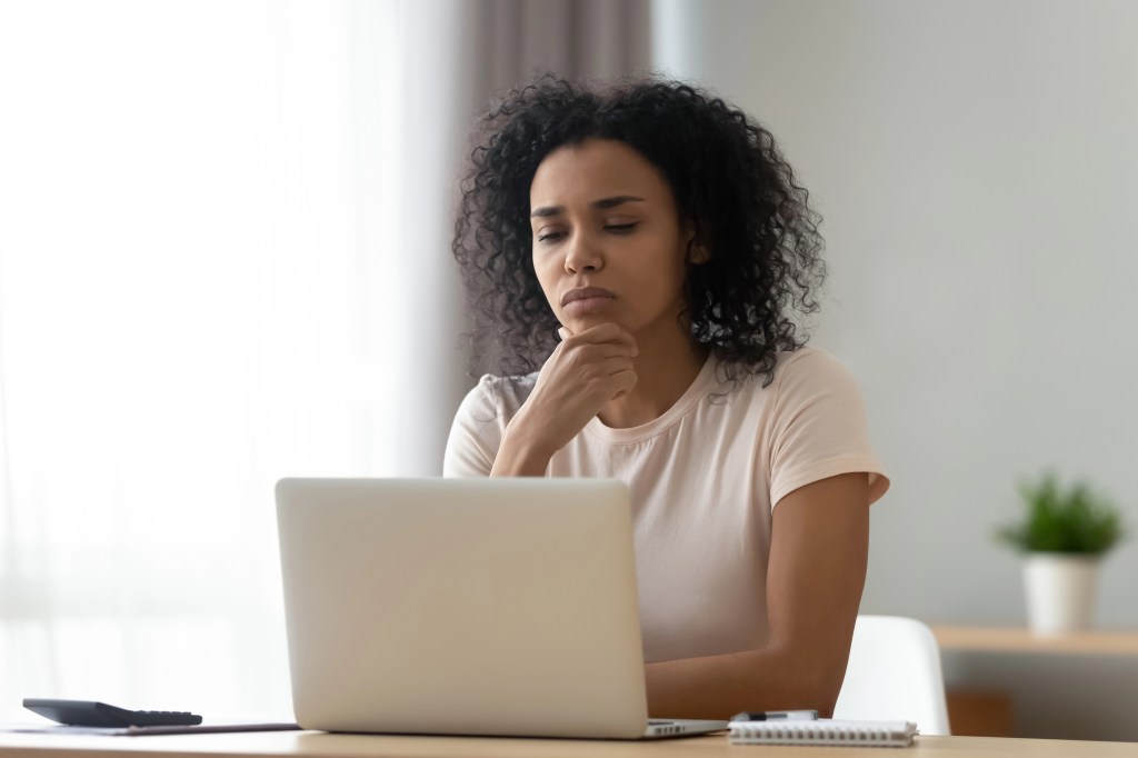 Black lady sitting at a desk in front of her laptop.