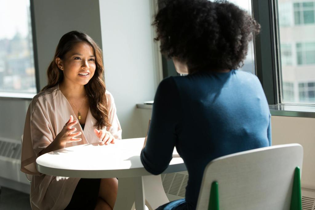 Two women sitting at a table talking.